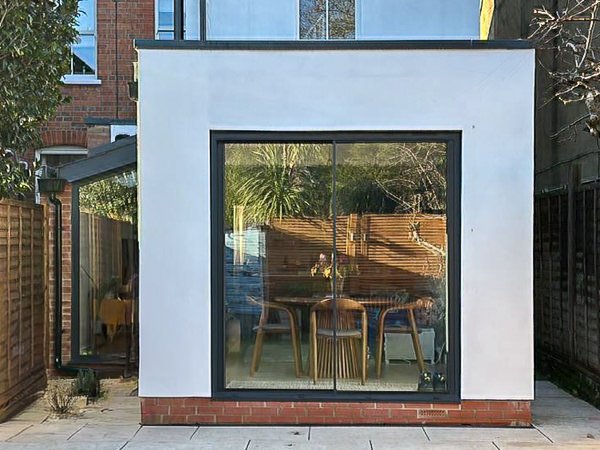 White rendered rear extension in Raynes Park with large sliding doors opening onto the garden